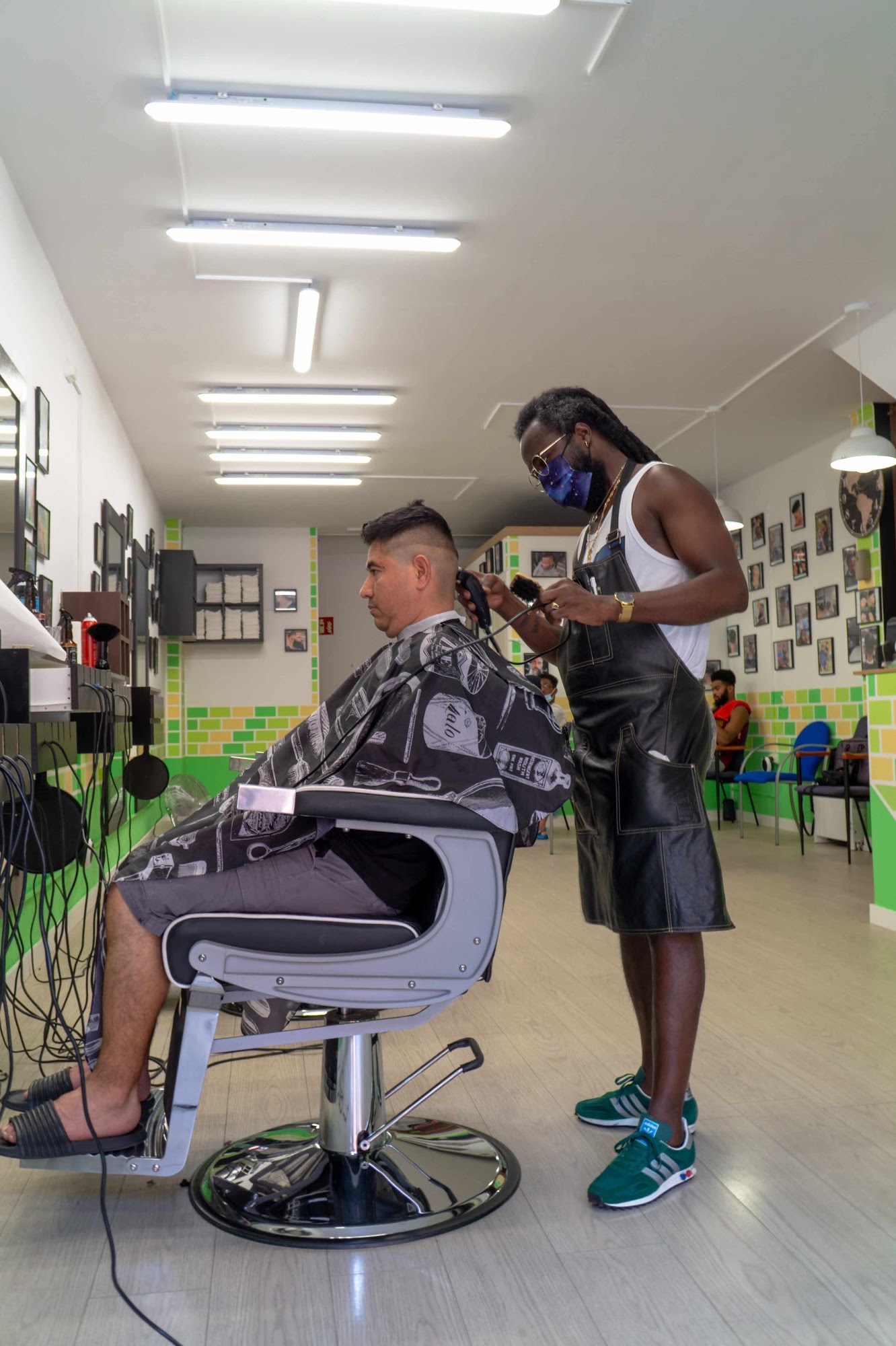 A barber giving a client a haircut inside One Love Barbershop